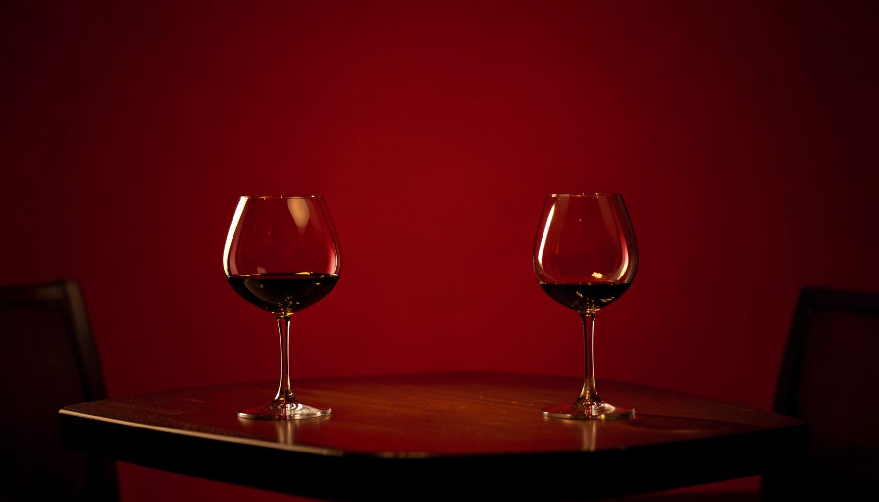 Dark atmospheric restaurant interior with warm amber lighting and wine glasses on a table